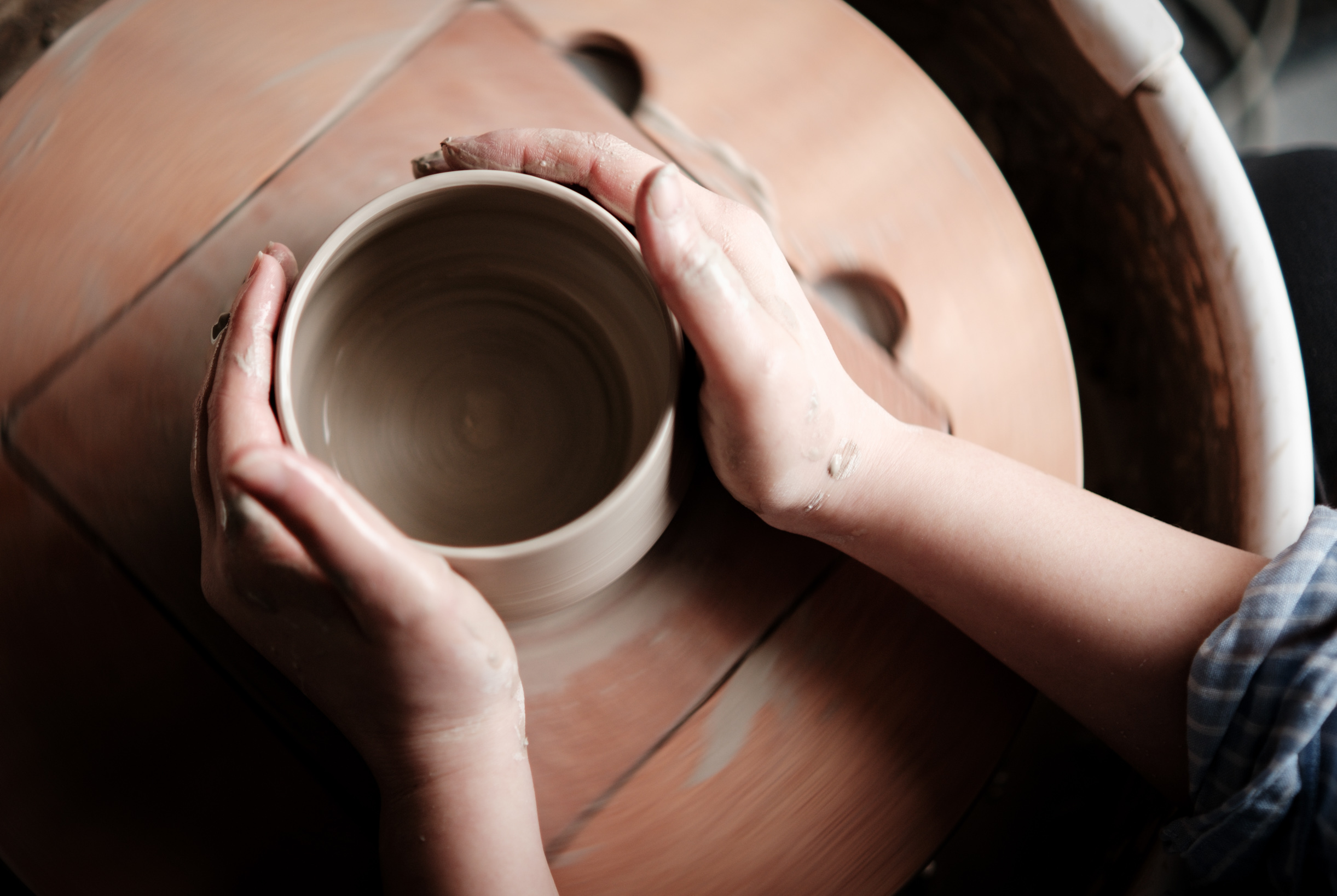 Artisan potter working at pottery wheel creating ceramic bowl - contact pottery class instructors and ceramic art studios